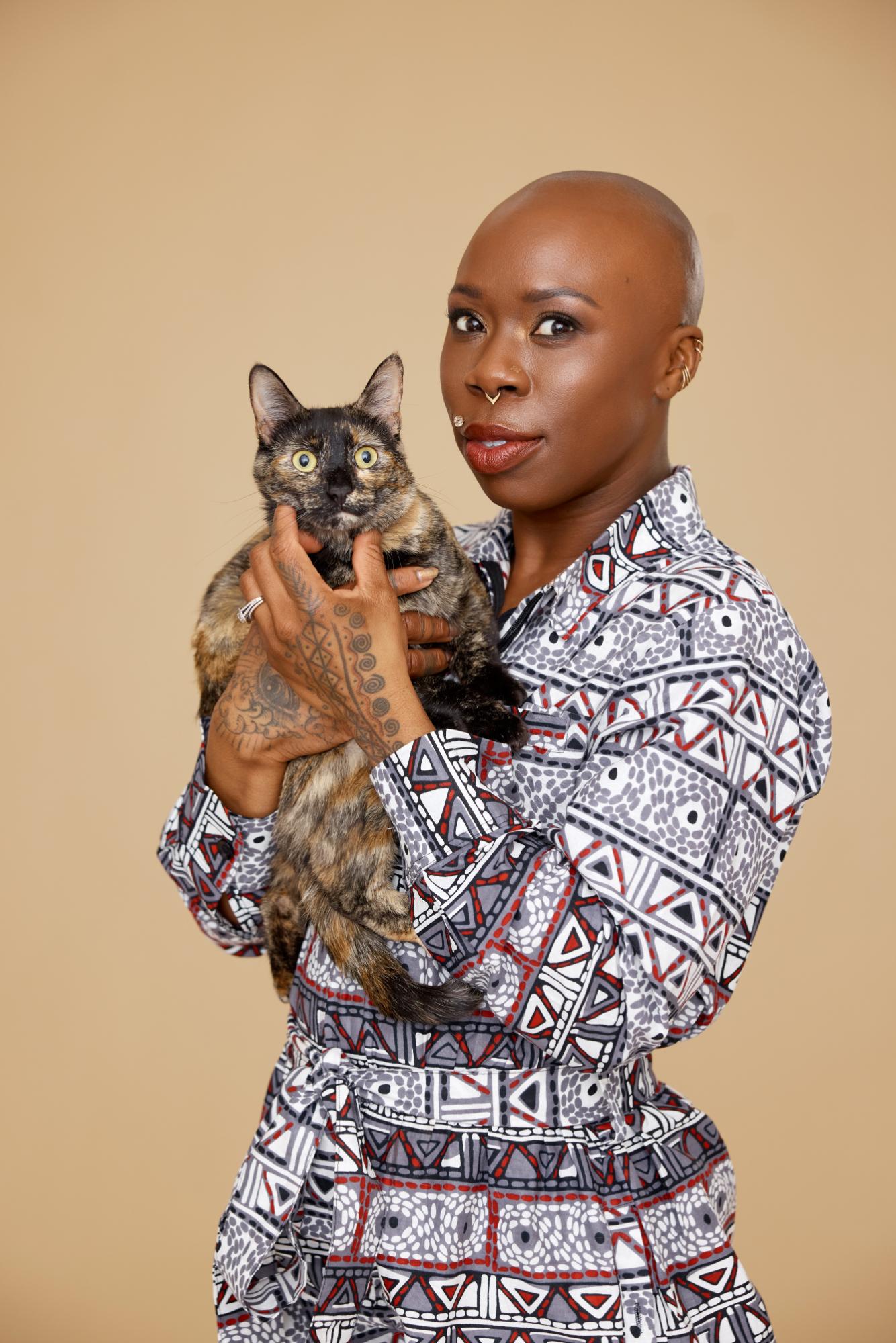 Person holding a tortoiseshell cat against a beige background