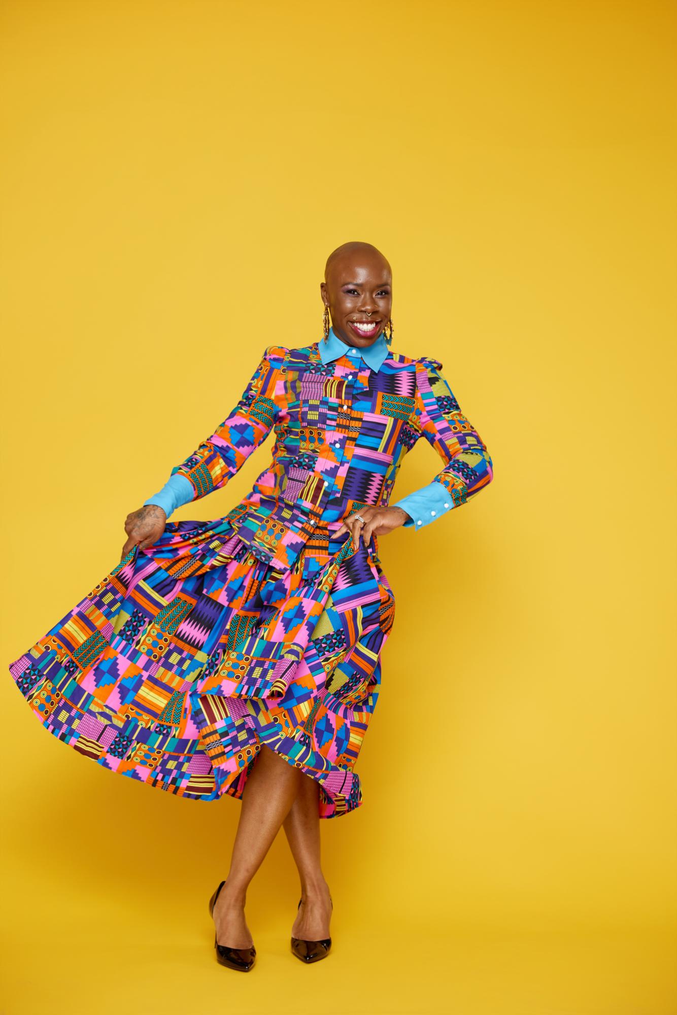 Woman wearing a colorful geometric patterned dress against a yellow background